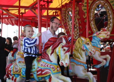 Brooklyn, New York - 23 Nisan 2019: Brooklyn'deki Coney Island Boardwalk'ta Hamurdan Geçişu sırasında Luna Park'ta Yahudi ortodoks aile yolculuğu Coney Island atlıkarıncası 