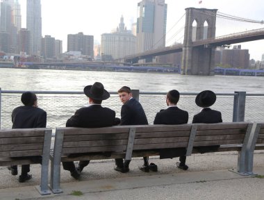 BROOKLYN, NEW YORK - MAY 2, 2019: Jewish orthodox teenagers enjoy outdoors near Brooklyn Bridge in New York clipart