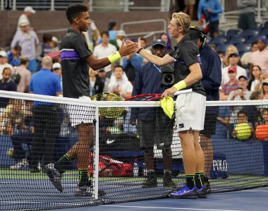 NEW YORK - AUGUST 27, 2019: Professional tennis player Dennis Shapovalov  of Canada (R) embraces Felix Auger Aliassime at the net following his win in the 2019 US Open first round match  clipart