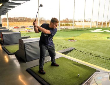 EDISON, NEW JERSEY - 8 ARALIK 2019: Oyuncu, Edison, NJ 'de bir numaralı eğlence merkezi olan Topgolf' te topa vurarak puan kazanır. Topgolf Entertainment Group küresel bir spor ve eğlence topluluğudur.
