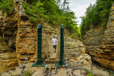 AUSable CHASM, NEW YORK - 22 AĞUSTOS 2020: New York 'un kuzeyindeki Ousable Chasm' da Avustralya Nehri üzerinden maceralı ip köprüsünü geçen ziyaretçi. Vadi 3,2 km uzunluğunda. 