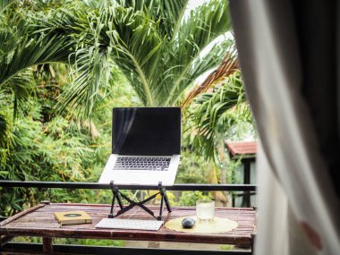 Masada dizüstü bilgisayar, arka planda yeşil tropik bitkiler