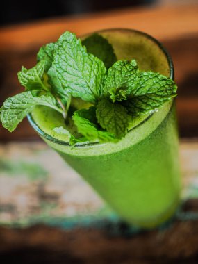 Ahşap zemin üzerinde nane yaprakları olan yeşil smoothie