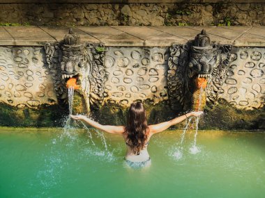 Suda dinlenen genç bir kadının arka görüntüsü, Bali 