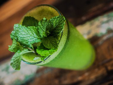Ahşap zemin üzerinde nane yaprakları olan yeşil smoothie