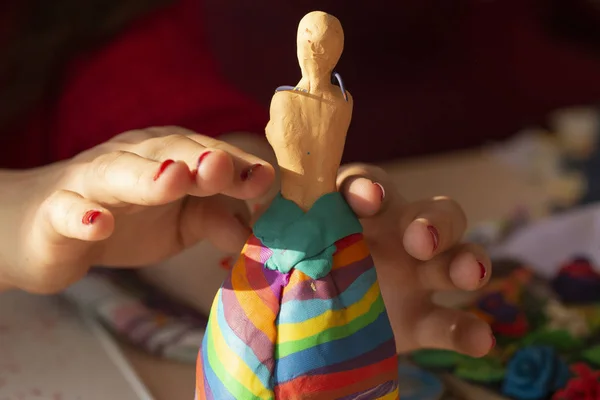 A girl molds a doll with her hands. Teaching students the art of modeling. Sculpture made of plasticine.