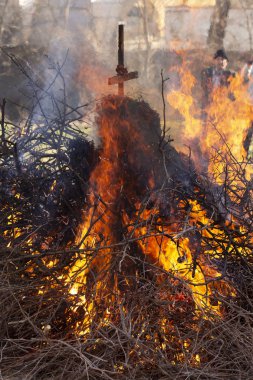 Yanan ateş. Shrovetide içinde büyük şenlik ateşi. Yanan ağaç dalları. İnsanlar ateşe bak. Pagan ayin baharın gelişini adanmış.