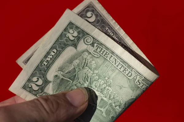 Två Dollarsedel Mans Hand Mot Röd Bakgrund — Stockfoto