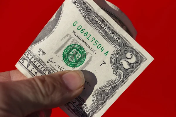 Två Dollarsedel Mans Hand Mot Röd Bakgrund — Stockfoto