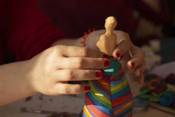 A girl molds a doll with her hands. Teaching students the art of modeling. Sculpture made of plasticine.