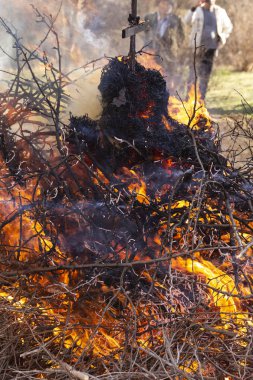 Yanan ateş. Shrovetide içinde büyük şenlik ateşi. Yanan ağaç dalları. İnsanlar ateşe bak. Pagan ayin baharın gelişini adanmış.