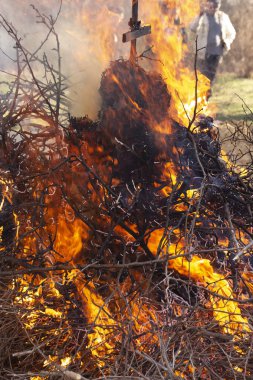 Yanan ateş. Shrovetide içinde büyük şenlik ateşi. Yanan ağaç dalları. İnsanlar ateşe bak. Pagan ayin baharın gelişini adanmış.