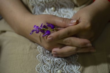 Annelik. Hamile bir kadının elleri. Menekşe çiçeği, bir bebeğe hamile kalma işareti.