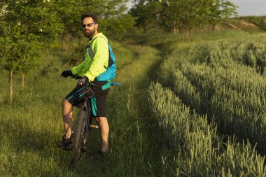 Bisikletçi MTB üzerinde sürmek. Freerider bir buğday tarlası aracılığıyla off-road sürmek. Eğitimdeki atlet. Agresif spor. Aşırı rekreasyon.
