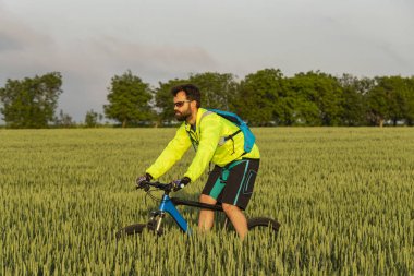 Bisikletçi MTB üzerinde sürmek. Freerider bir buğday tarlası aracılığıyla off-road sürmek. Eğitimdeki atlet. Agresif spor. Aşırı rekreasyon.
