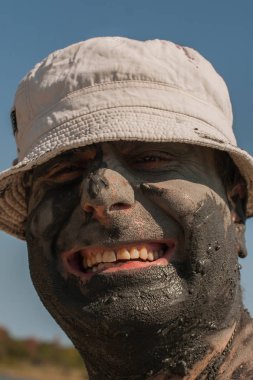 Karadeniz kıyısında Mud Spa tedavileri. Yüzleri yapan kirli bir adamın portresi. Bir adam Bulgaristan'da tatil yapıyor - o olabilir gibi.