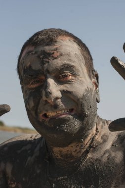 Karadeniz kıyısında Mud Spa tedavileri. Yüzleri yapan kirli bir adamın portresi. Bir adam Bulgaristan'da tatil yapıyor - o olabilir gibi.