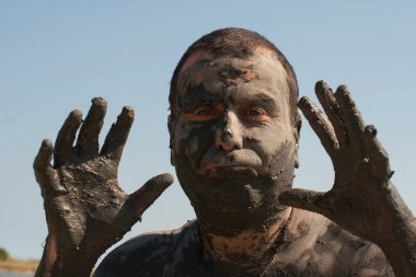 Karadeniz kıyısında Mud Spa tedavileri. Yüzleri yapan kirli bir adamın portresi. Bir adam Bulgaristan'da tatil yapıyor - o olabilir gibi.