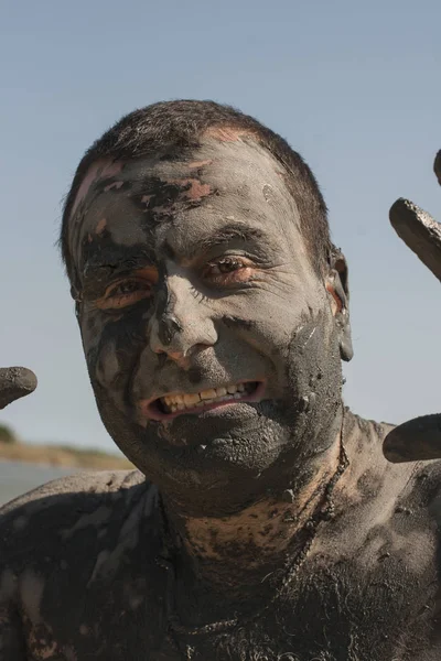Mud Spa treatments on the Black sea coast. Portrait of a dirty man making faces. A man is vacationing in Bulgaria - as he can.