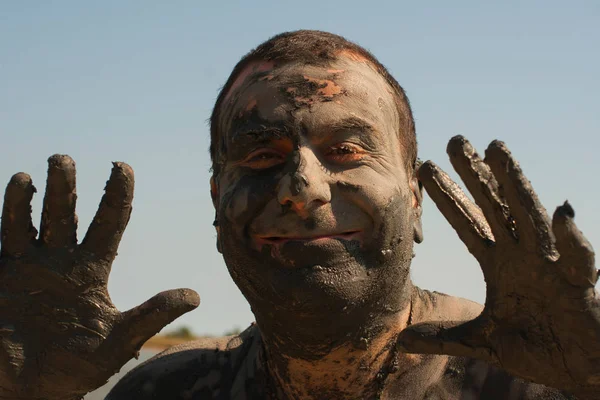 Mud Spa treatments on the Black sea coast. Portrait of a dirty man making faces. A man is vacationing in Bulgaria - as he can.