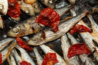 Fırın tepsisinde pişirilmiş domates ve soğanlı Baltık ringası..