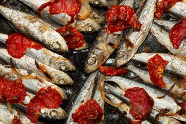 Fırın tepsisinde pişirilmiş domates ve soğanlı Baltık ringası..