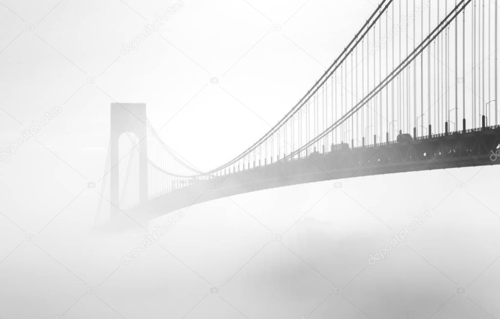 Black and white image of a bridge hidden in the fog. The Verrazano -Narrows Bridge is a double -decked suspension bridge that connects the New York City boroughs of Staten Island and Brooklyn