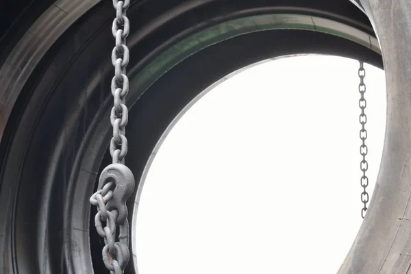 Tire and chain against the white sky. Background.A fragment of a huge tire for heavy vehicles. Chains fix the position of the tire.