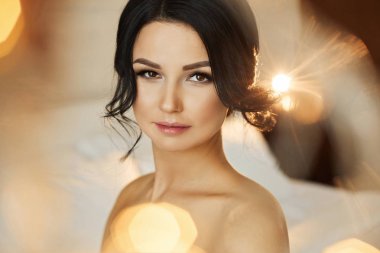 Seksi ve güzel esmer modeli kız gülümseyerek ve lüks iç poz çıplak omuz ile mükemmel makyaj ile şık saç modeli ile