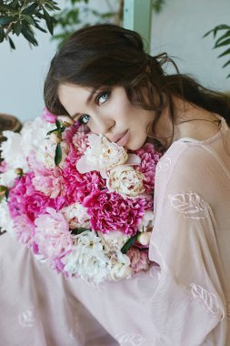 Güzel ve seksi esmer modeli kız büyük baştan çıkarıcı dudaklar ve büyük elleri pembe ve beyaz çiçekler Buket bej elbiseli mavi gözlü