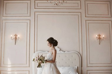 Güzel genç gelin, şehvetli esmer modeli kız lüks vintage iç, onun elinde çiçeklerle poz moda gelinlik şık saç modeli ile