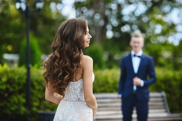 Красива і модна брюнетка модель дівчина з сексуальним тілом і з весільною зачіскою в стильному білому мереживному платті, що йде до свого хлопця — стокове фото