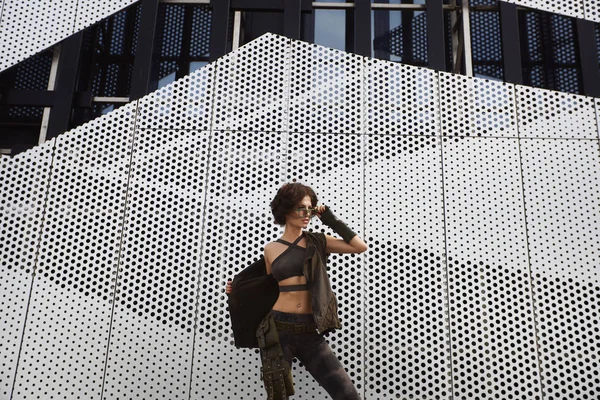 运动和性感的黑发健身模特女孩与完美的身体在时尚的太阳镜和军服, 脱下她的背心, 并在一个城市的户外摆姿势 — 图库照片