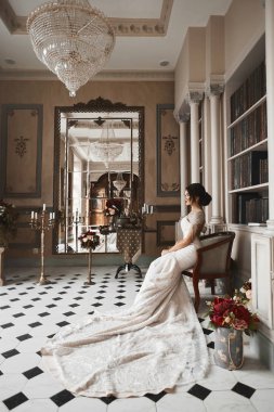 Antika sandalye ve vintage iç poz güzel ve şık esmer modeli kız lüks dantel elbise mükemmel seksi vücut ile parlak makyaj ile oturur