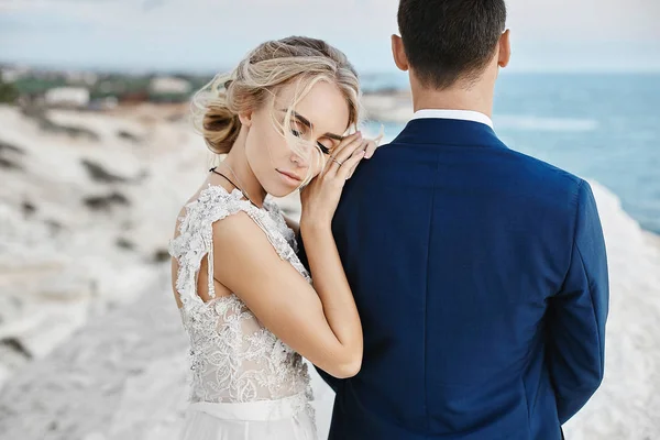 Şık beyaz dantel elbise şık mavi elbiseli yakışıklı adam üzerinde yalın ve Adriyatik Denizi'nin kıyısında beyaz kayaya üzerinde poz güzel genç sarışın model kız — Stok fotoğraf