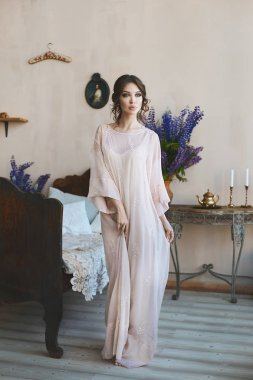 Vintage İtalyan iç antika yatağın yakınında poz gri moda elbise büyük seksi dudakları ile güzel ve şehvetli esmer model kız