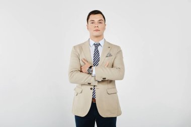 Çizgili kravat ile beyaz gömlek şık ve yakışıklı genç brunet adam, bej blazer ve koyu kot beyaz arka planda poz, izole