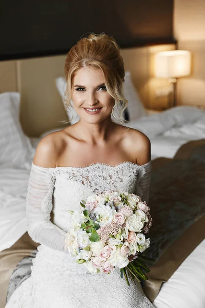 Güzel ve mutlu sarışın model kız düğün dantel içinde onun el gülümsüyor ve şık lüks iç poz buket çiçek elbise — Stok fotoğraf