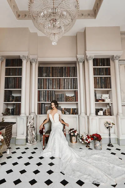 Szép és divatos barna lány hosszú csipke ruhában pózol a vintage luxus belső, a palota az apartmanban esküvő előkészítés — Stock Fotó