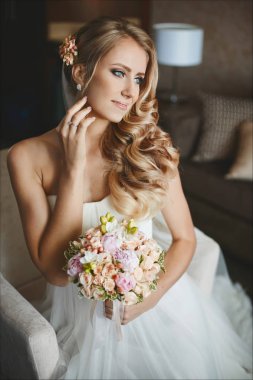 Genç ve güzel gelin, düğün saç modeli ile elleri buket beyaz elbiseli ve hafif makyaj ile şehvetli sarışın model kız
