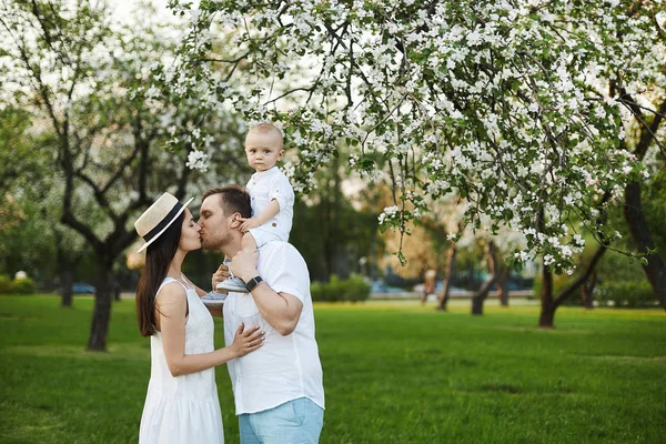 Hermosos padres jóvenes y su pequeño hijo lindo divertirse en el parque verde — Foto de Stock