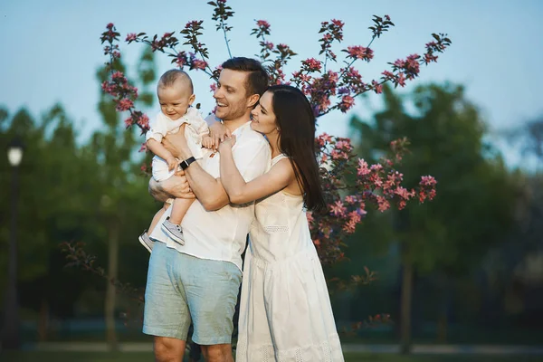 Schöne junge Eltern und ihr süßer kleiner Sohn haben Spaß im grünen Park — Stockfoto