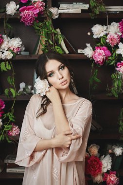 Gri elbiseli genç esmer modeli güzel ve seksi kadın Kitaplığı'nda çiçeklerle poz