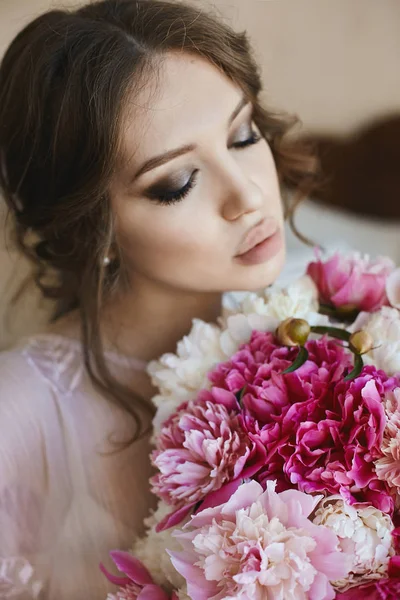 Portrait of beautiful young brunette woman with closed eyes and big seductive lips, with bouquet of flowers in her hands — Stock Photo, Image