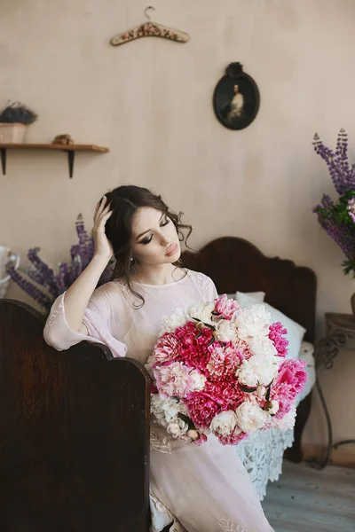 Gyönyörű barna lány nagy csábító ajkak és a divatos ruha, rózsaszín és fehér virágokkal, a kezében nagy csokor kék szemmel — Stock Fotó
