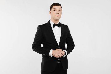 Şık ve yakışıklı duygusal delikanlı Beyaz gömlekli ve şık siyah takım elbiseli beyaz arka plan izole papyon ile