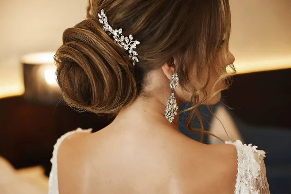 Penteado de casamento - mulher jovem de cabelos castanhos na moda, em um vestido de cadarço e com brincos — Fotografia de Stock