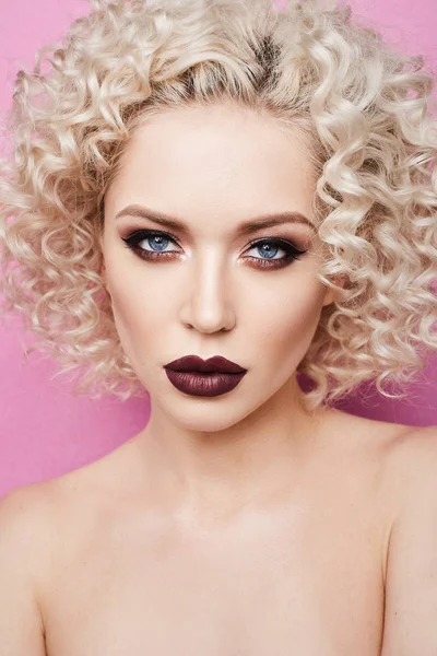 Schöne und modische Modell Mädchen mit erstaunlichen blauen Augen, mit lockigen blonden Haaren und mit professionellen hellen Make-up isoliert auf dem rosa Hintergrund — Stockfoto