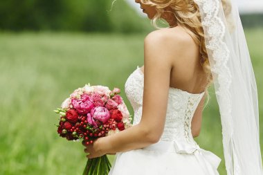 Seksi ve güzel sarışın model kız içinde mükemmel vücut ile düğün elbise poz çiçek bir buket içinde onun elleri açık havada