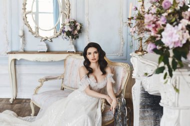 Güzel genç gelin, çıplak omuzları ile şık ve moda gelinlik seksi esmer model kız kanepede oturur ve lüks Vintage iç poz